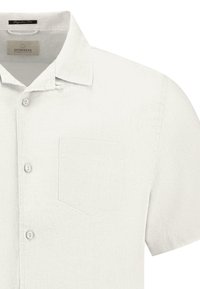 Kortsleeve hvit skjorte laget av teksturert stoff med krage som kan kneppes, med en brystlomme og en lett strukturert design.