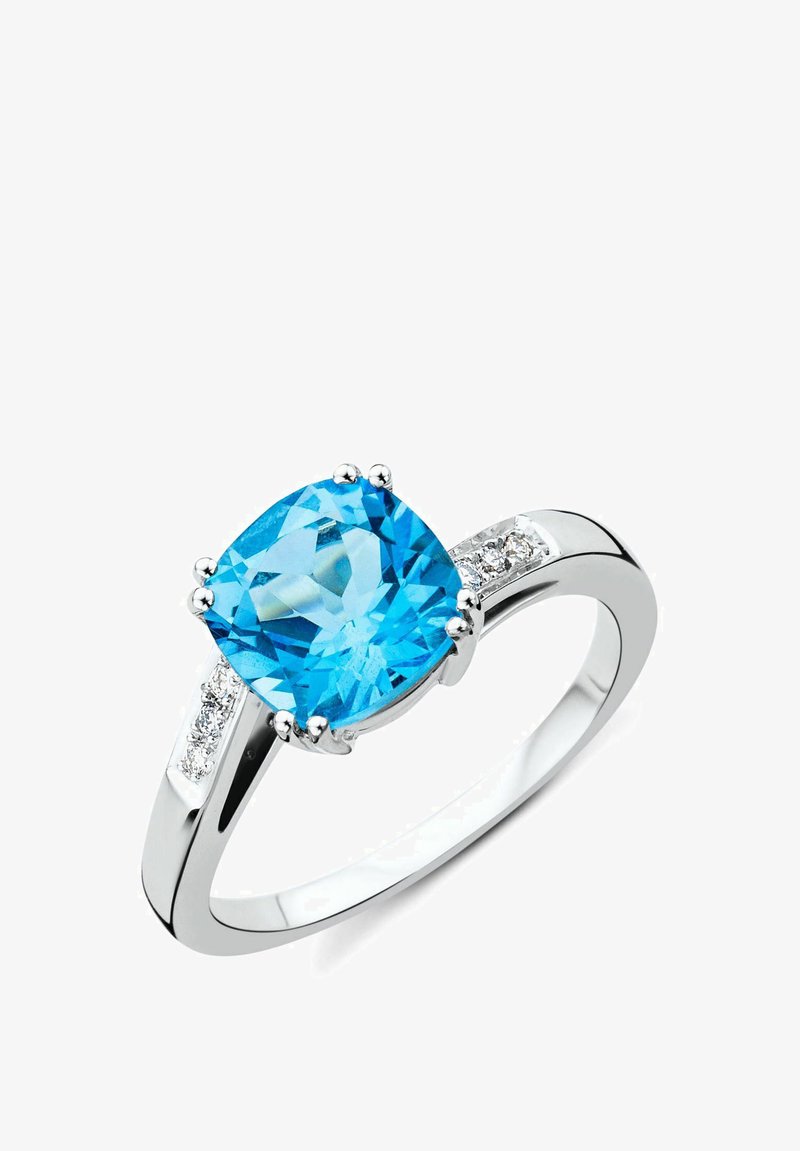 Srebrn prstan z velikim, blazino rezanim modrim draguljem, obdan z manjšimi prozornimi kamni na obroču. Gladka, polirana površina.