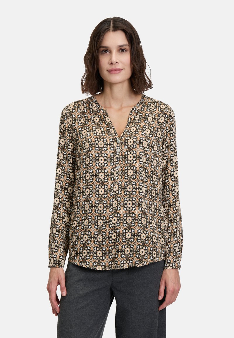 Langärmlige Bluse aus gemustertem Stoff mit floralen Motiven in Beige, Schwarz und Braun, mit einem V-Ausschnitt und einem Knopf-Accessoire an der Vorderseite.