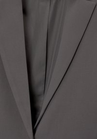 Grauer Blazer mit Reverskragen, glatter Textur und taillierte Passform. Der Stoff ist leicht und leicht strukturiert.