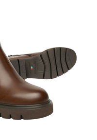 Stivale in pelle marrone con suola in gomma spessa, un stivale che mostra il motivo del battistrada e il dettaglio della bandiera italiana sulla suola.