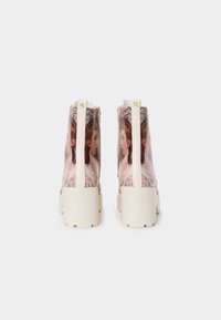 Transparante enkelboots met een bedrukt ontwerp met klassiek portretten. Stevige witte zolen en een gestructureerde ritsdetails aan de achterkant.