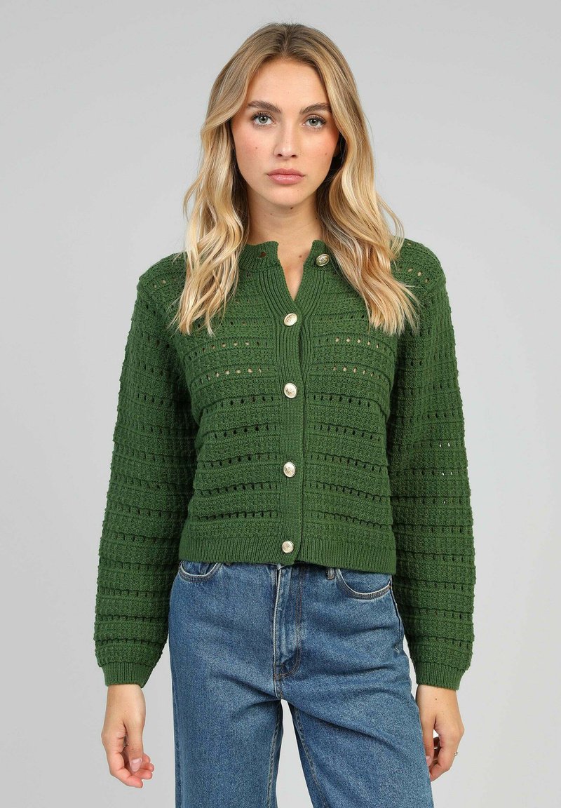 Cardigan tricoté vert avec un motif texturé, dotée d'un design cropped, manches longues et grands boutons sur le devant.
