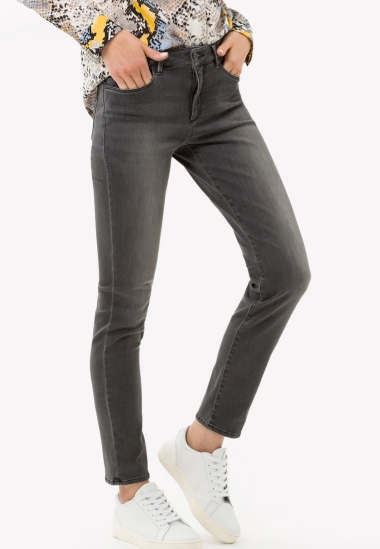 Jeans de denim gris con un corte ajustado, cinco bolsillos y un desvanecimiento sutil, combinados con zapatillas blancas. La tela tiene una textura suave.