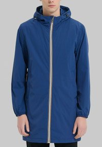 Veste légère bleue avec capuche, dotée d'une fermeture éclair à l'avant avec un accent rayé. Poignets élastiques et poches latérales. Texture lisse.