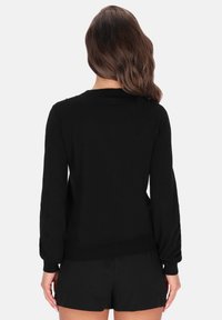 Suéter negro de manga larga con puños y dobladillo acanalados, hecho de material suave, con un escote clásico y un corte relajado.