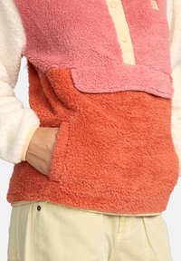 Fleece pullover met roze, koraal en roomkleurige secties, met een ronde halslijn met knopen en een zijzak op het koraal paneel.