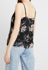 Schwarzes Blumenshirt mit dünnen Trägern, das eine Mischung aus rosafarbenen und blauen Blumenmustern zeigt und aus einem lockeren, leichten Stoff gefertigt ist.