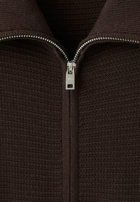 Brązowy, fakturowany sweter na zamek z detalem w postaci srebrnego zamka. Materiał ma wzór tkany i wysoką stójkę.