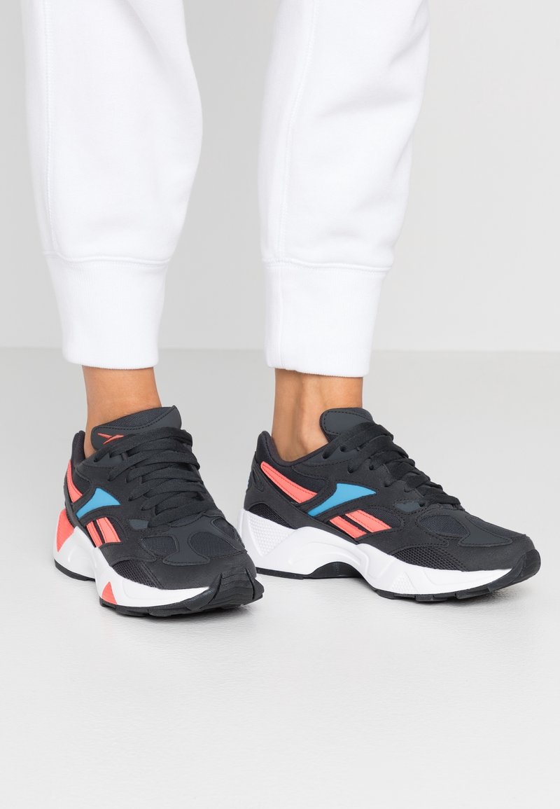 Czarne sportowe sneakersy wykonane z siateczkowych i syntetycznych materiałów. Posiadają różowe i niebieskie akcenty, wyściełany kołnierz oraz teksturowaną gumową podeszwę.