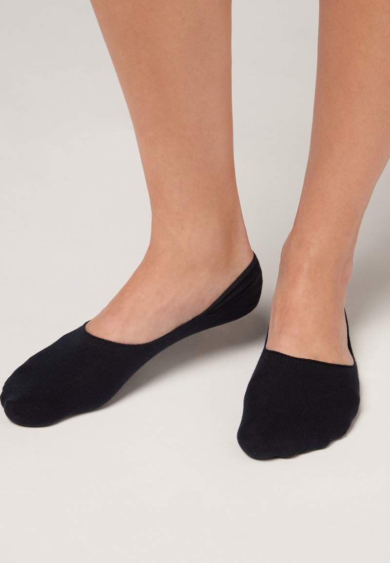 Calcetines negros invisibles hechos de un tejido suave y elástico, con un diseño bajo que cubre el pie y permanece oculto bajo el calzado.
