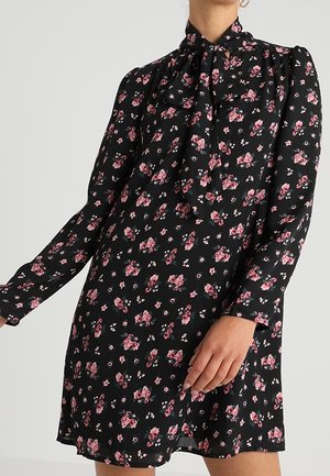 Abito nero floreale con maniche lunghe, caratterizzato da un collo alto e un dettaglio a fiocco; decorato con stampe floreali rosa e bianche in tutto.