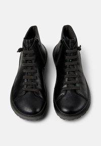 Een paar zwarte leren hoge schoenen met zijritsen en zwarte veters, bovenaan getoond op een witte achtergrond.