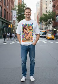 Weißes T-Shirt mit buntem Grafikdesign, das eine Frau im Bikini zeigt, umgeben von dem Text „Good Vibes“; blaue Jeans und weiße Sneaker.
