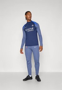 Navy and light blue athletic outfit featuring a long-sleeved top with a high collar and printed logo, matched with slim-fit pants.