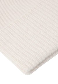 Witte ribbeltextiel met een zachte, donzige textuur; heeft parallelle lijnen en een gevouwen rand, wat een luxe uitstraling geeft.