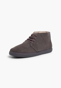 Bottines en suede gris foncé avec bout rond, design à lacets, œillets dorés et semelle en caoutchouc texturé. Intérieur doublé pour le confort.