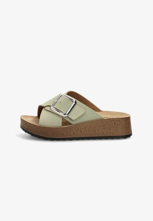 Sandalia con plataforma verde claro, con una amplia correa cruzada, hebilla grande plateada, suela con textura de corcho y parte inferior negra con dibujo antideslizante.