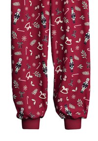 Joggers en tissu rouge présentant un motif décoratif de casse-noix, de cannes en sucre, de flocons de neige, de chevaux à bascule et de feuillages festifs.