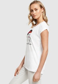Weißes Baumwoll-T-Shirt mit einem bunten grafischen Design einer Frau mit einem blühenden Haaraccessoire. Kurzärmelig und mit lockerer Passform.
