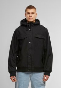 Black hooded jacket with button closure, zip and flap pockets, ribbed cuffs and hem, made of durable fabric with a smooth texture.