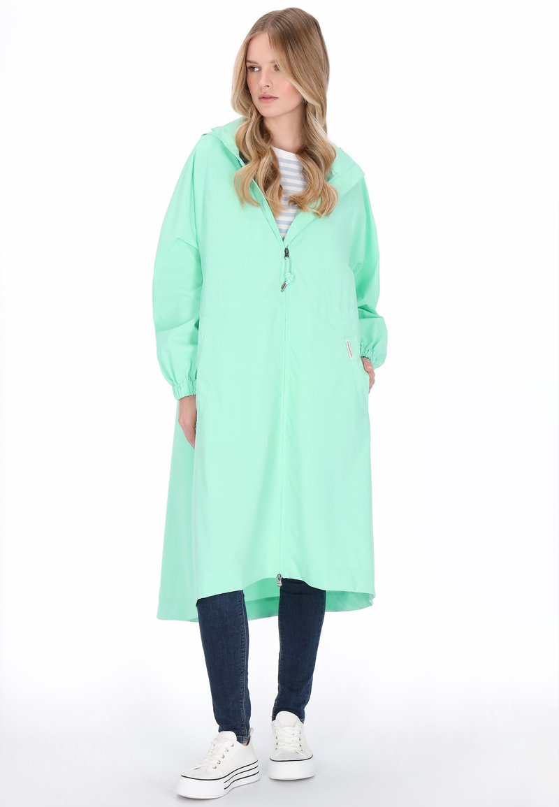 Világoszöld, könnyű esőkabát kapucnival, elülső cipzárral és rugalmas szegélyekkel. Oldalzsebekkel és középhosszúságú kialakítással.