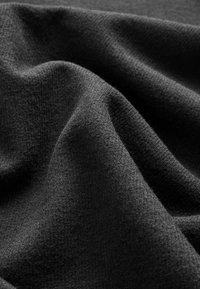 Tissu noir avec une surface douce et texturée, présentant des variations subtiles de teinte et une apparence tissée lisse.