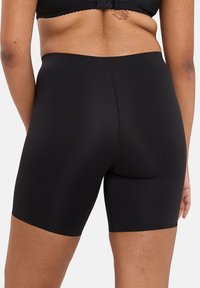 Shorts de shapewear noirs taille haute avec une texture lisse, coupe ajustée et longueur mi-thigh, conçus pour le confort et le soutien.