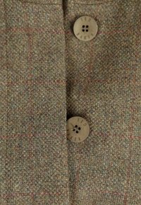 Tela de tweed marrón con un sutil patrón de cuadros en rojo y dos botones beige grabados con "TED BAKER."