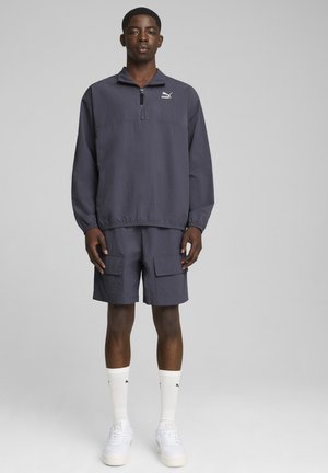 Herre grå pullover jakke med kvart-zip, parret med matchende shorts. Tekstureret stof, elastiske manchetter og logo detalje på brystet.