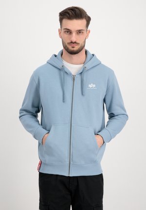Light blue zip-up hoodie made of soft fabric, featuring a front logo, drawstring hood, and kangaroo pockets. Ribbed cuffs and hem.