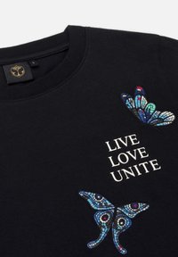 Zwarte katoenen sweatshirt met geborduurde kleurrijke vlinderontwerpen en de tekst "LIVE LOVE UNITE" in het wit.