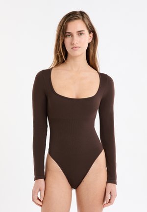 Body de manga larga marrón con escote redondo y piernas de corte alto. Confeccionado en una tela lisa y ajustada con un diseño sin costuras.