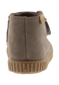 Bottine en suède marron avec une semelle en caoutchouc texturée. Présente une couture et une petite étiquette en cuir à l'arrière. Design à bout arrondi.