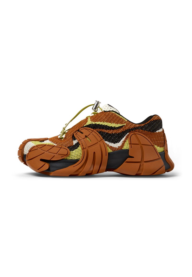 Scarpa da allenamento arancione e nera con tomaia in rete testurizzata, suola in gomma e design distintivo della punta; presenta un sistema di lacci regolabile.