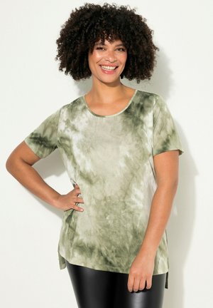 Zelené tričko s potiskem tie-dye, krátké rukávy, kulatý výstřih a boční rozparky. Měkká tkanina s rozmazaným vzorem v různých odstínech zelené.