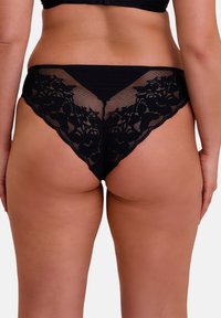 Des culottes en dentelle noire avec un dos en maille transparente orné de dentelle florale, un tissu léger et une coupe basse.