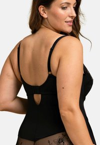 Bodysuit noir avec bretelles ajustables, détails en dentelle et dos en trou de serrure. Présente une texture lisse et des accents floraux sur un tissu transparent.