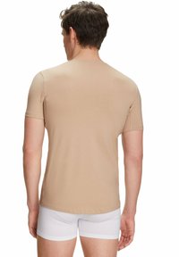 Beige short-sleeve t-shirt, smooth texture, fitted design. Worn with white underwear, showing a plain back view without additional details.
