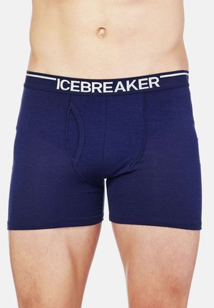 Boxers en coton bleu foncé avec une ceinture flexible affichant le logo "ICEBREAKER" en blanc. Présente une ouverture frontale fonctionnelle.