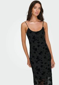 Czarna sukienka na ramiączkach typu slip dress z kwiatowym wzorem, wykonana z fakturowanej tkaniny o aksamitnym kwiatowym motywie oraz przezroczystym mankietem na dole.