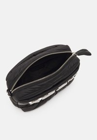 Borsa nera in nylon trapuntato con zip e accessori in metallo argentato. Forma ovale, chiusura con zip superiore, texture liscia e interni spaziosi.