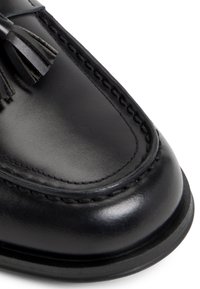 Schwarze Lederloafer mit klassischem Design, glatter Textur, kontrastierenden Nähten und dekorativen Quasten auf der Vorderseite.