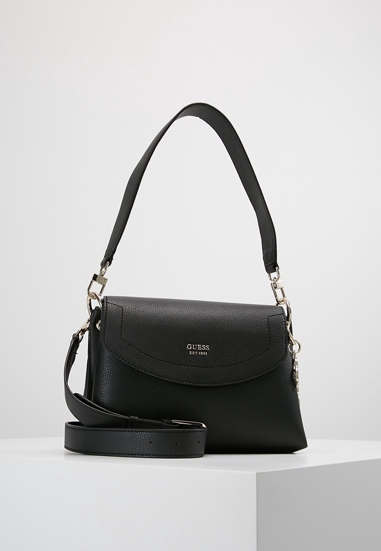 Musta nahkainen käsilaukku, jossa on pyöreä läppä, irrotettava hihna ja hopeinen varustus. Sisältää kohokuvioidun logo ja sileän pinnan.