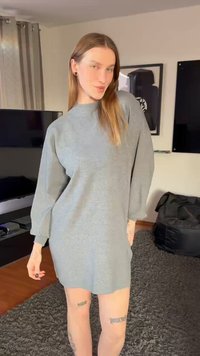 Langermet, oversized kjole i mykt grått stoff. Rund hals med senkede skuldre og lett innsnevrede ermer. Synlige tatoveringer på bena.