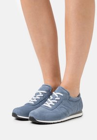 Wildledersneaker in Hellblau mit strukturierten Akzenten. Ausgestattet mit weißen Schnürsenkeln und einer schwarzen Gummisohle mit einem weißen Streifen.