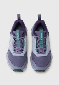 Chaussures de sport violettes et bleu clair avec tige en maille, lacets plats, languettes de tirage et accents contrastés. Comprend des détails de logo sur les côtés.