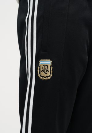 Sorte sportbukser med hvide sidestriber og et guld- og blåt broderet AFA-emblem på det øvre lår.