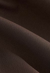 Textil maro cu o suprafață netedă, ușor texturată, având variații subtile de nuanță și un model țesut.