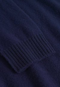 Mörkblå stickad tröja med ett mjukt, strukturerat tyg och ribbade mudd detaljer, som visar en jämn yta och rik färgdjup.